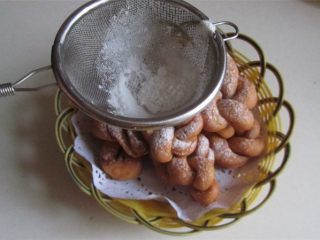 15、酥脆麻花,将捞起的麻花装入篮中, 在上面撒上糖粉;