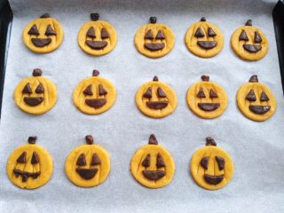 18、万圣节不给糖就捣蛋——南瓜饼干,把可可面团分割出来的嘴巴，眼睛沾点水贴到南瓜饼胚上，多出来的一些小碎料用来做南瓜柄，同时预热烤箱160度