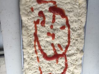 1、腊肉香肠披萨,发酵好的面装盘拿叉扎眼，刷上披萨酱。