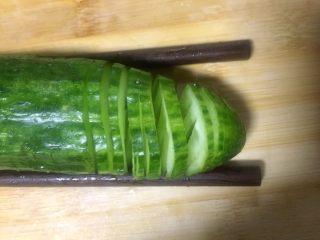 8、#吉祥年夜菜#青龙送福~蓑衣黄瓜,然后反转180度，同样用筷子垫在黄瓜底部，正常切的方式，同样也是在筷子处止刀