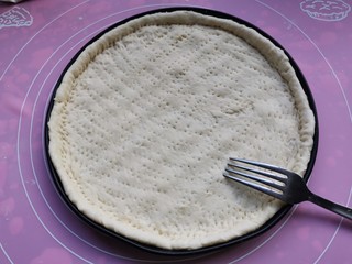 12、黑椒牛肉披萨,放入披萨盘，边缘要多出来点，用叉子戳满小孔