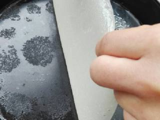 5、自制凉皮,锅里放水烧开, 披萨盘抹一点油, 放一勺面糊在盘底均匀摊开(薄薄一层), 放在开水面上加热,盖上锅盖, 颜色接近透明就可以了, 拿出来放凉, 从边上慢慢把凉皮揭下来, 再抹点油放入面糊继续上面的做法直到面糊用完，每片凉皮好了都要抹油，以免摞起来沾上
