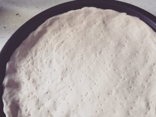 3、金枪鱼脆皮肠披萨????,披萨盘刷油。薄薄一层就好。将面团平铺。用叉子插孔若干。