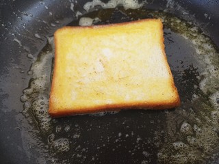 4、煎蛋蔬菜培根三明治,然后把土司放进去煎