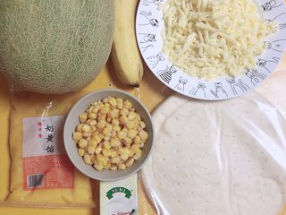 1、蜜瓜蔬果披萨,准备好食材。哈密瓜、披萨饼底、玉米粒、香蕉、奶黄馅、淡奶油、芝士碎。