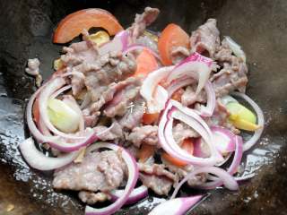 11、孜然牛肉炒拉条 家常面条百吃不厌的美味做法,牛肉片稍微变色后下入西红柿片和洋葱丝，翻炒至洋葱片稍微断生。