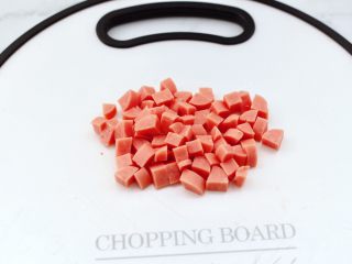 3、蛋挞火腿时蔬小披萨,火腿肠去外皮，用刀切成小丁。