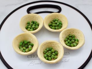 6、蛋挞火腿时蔬小披萨,先在蛋挞皮里放入青豆。