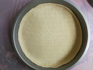 8、薄底香肠披萨,放入9寸披萨盘中，用手整理边沿使面片与披萨盘贴合平整，然后用叉子在面片上扎出小洞，以防烘烤时鼓起