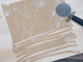 2、自制全麦意面(不用意面机),用涂了面粉的擀面棒将面团擀得越薄越好，如果很粘手，再撒上一些面粉。