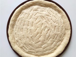 7、虾仁披萨,将披萨胚放进披萨盘里，用叉子扎孔；