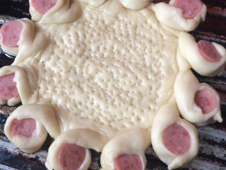 6、懒人披萨,将火腿肠切三毫米厚的块，放在切开的饼边上，与另一个饼边叠加在一起，使圆面朝上，底部扎眼，放烤箱烤5分钟