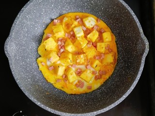 9、宝宝辅食—香肠馒头抱蛋,蛋液半凝固时,放入馒头块,撒上香肠,继续小火满煎