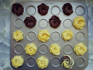 8、双色玫瑰曲奇,将做好的面糊装入大号裱花袋，用六齿花嘴挤在烤盘中，按照从内心螺旋状挤出花型。混色的玫瑰是将两种颜色的面糊分两侧同时装入裱花袋