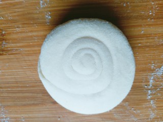 6、千层油饼,然后从一头边慢慢抻长边开始盘起,最后收尾放到底下,用手稍微摁扁