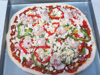 23、货真料足媲美必胜客的【海陆至尊披萨】,再撒一层马苏里拉芝士碎后放入青椒、红椒及熟虾仁,撒上玉米粒、豌豆粒,撒上最后一层芝士碎