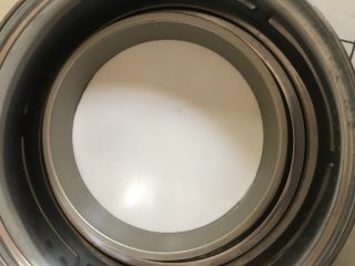 7、自制凉皮,取一个披萨盘，舀入一勺面糊，放入蒸锅蒸两三分钟，一定要开锅放入，而且要盖上锅盖蒸。