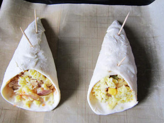 4、匹萨甜筒,放到铺好油布的烤盘中。用牙签再次固定一下重合的饼皮边缘