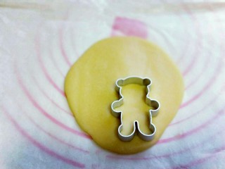 9、#感恩节食谱#嘻笑的熊宝宝饼干,取下上面的油纸,用小熊模具压出小熊图案来,小心取下小熊饼干,放入烤盘中,将面团全部压完。