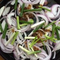 3、生焗海鲜大杂烩,将洋葱丝、葱段、大蒜铺在铁板上！铺满一层即可！没有铁板的可以用披萨盘，平底锅等等