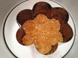 5、芒果慕斯,把拌好的饼干碎铺在模具底部，要压实，放入冰箱冷藏30分钟以上至凝固，