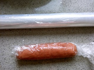 8、清凉西瓜曲奇饼干,红色的面团揉成圆柱形，放进模具里，可以用保鲜膜的桶来帮忙，放冰箱里冻30分钟