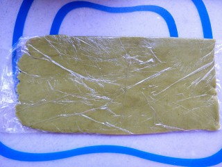 9、清凉西瓜曲奇饼干,把绿色的面团放进保鲜袋，固定出合适的宽度和长度，用擀面杖擀均匀