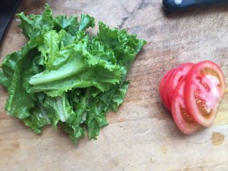 8、至珍全虾堡,烤虾的时候我们可以把生菜洗一洗，撕成小瓣；西红柿洗一洗，切成薄片。