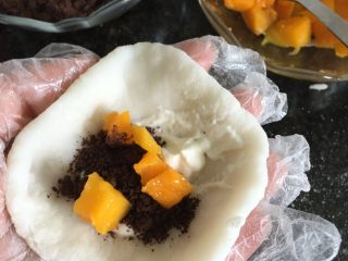 12、奥利奥芒果雪媚娘,12.压扁,放进适量淡奶油、饼干屑、芒果果肉,收紧开口即可,然后收口朝下放进圆形模具中,再放入冰箱冷藏一小时以上口感会更好;