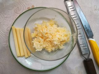 3、墨鱼热狗芝心披萨,把块状芝士切出几条条状的芝士，剩下的用奶酪刨刨成芝士碎备用。