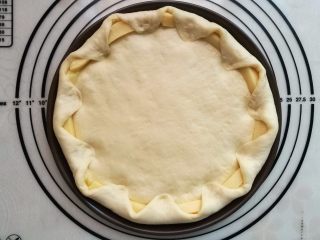 9、墨鱼热狗芝心披萨,把大出来的饼皮向里折入压紧，包住芝士条。