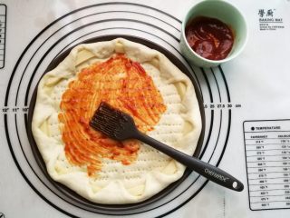 11、墨鱼热狗芝心披萨,把意粉酱涂满整个饼底。