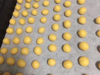 11、扁桃仁一口酥,烤盘里铺上油纸，如果是不沾烤盘就不用油纸，我家不沾小烤盘装不下，所以用了大的，两手揪成小粒，搓圆后放入烤盘中，时间不能太长要快