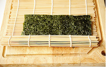 4、创意无限的花样寿司【小花寿司】,借助寿司帘卷起,使海苔紧紧包住米饭;