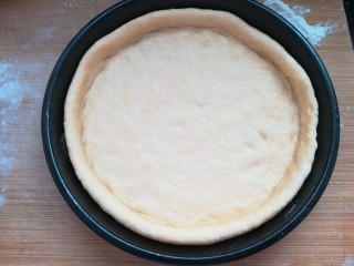 15、自制披萨,把披萨盘刷少许油,把面皮放入披萨盘,边上用手捏挤出一条边。