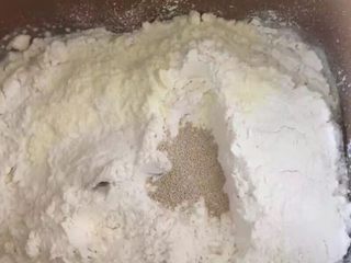 1、自制麦辣鸡腿汉堡,除黄油之外稍后添加，其它材料全部放入面包机中，按照先液体后固体的顺序依次加入，酵母粉放在最上面，开启揉面程序20分钟