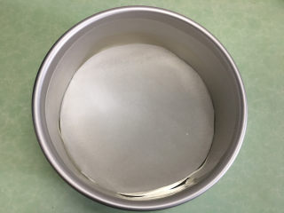 2、8寸芒果慕斯蛋糕,将剪好的圆形油纸铺在蛋糕模具底部。