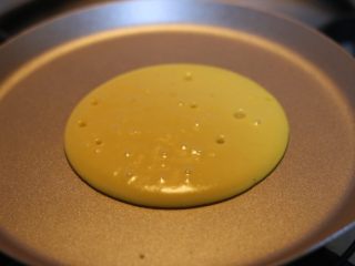 11、铜锣烧,面糊会自动向周边摊开，形成圆形○，待表面冒出许多小孔且暂停时，将其翻面。