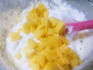 16、抹茶双味芝士生日蛋糕,奶酪糊和奶油充分拌均后倒入3分之二的芒果丁再次搅拌均匀