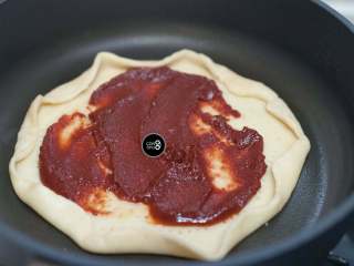 6、没有烤箱照样做出香浓芝士风味薄底披萨,锅底抹一层油，放入饼皮。抹上厚厚的番茄酱。