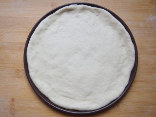 6、番茄鸡肉肠披萨,将面团擀成圆形饼状，均匀铺在披萨盘上，将边缘整理整齐。