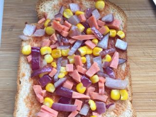 5、自制吐司披萨,蕃茄酱刷在面包上打底，铺上前面准备的材料