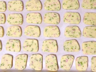 17、香葱芝士饼干,烤箱预热180度，烤盘内铺上油纸，均匀地摆上切好的饼干胚子，要预留空间防止粘连，烤制的时候会膨胀