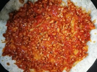 17、萨拉米白香肠培根薄底披萨(平底锅版),把披萨皮放入平底锅,上面涂上炒好的披萨酱料,四周留空白。(薄底的只要涂薄薄一层即可,我涂得厚了点????)