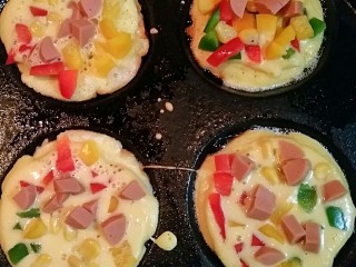 6、Mini披萨,在粉糊上面撒上彩椒，火腿肠，甜玉米粒，加盖小火焖5分钟。