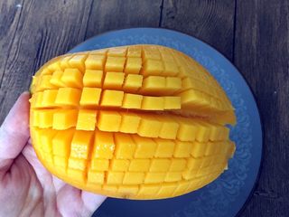 1、缤纷水果披萨,芒果对半切开，横竖切出小颗粒，往外一推，果肉就很容易切下来。