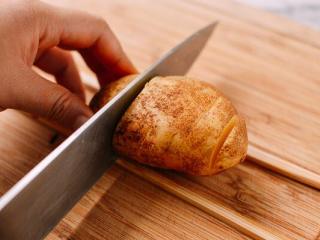 1、风琴土豆,土豆洗干净切薄片,用两根筷子横在土豆两边,刀切下去碰到筷子停手。土豆切成底部连接的风琴薄片。非常考验刀功哦!