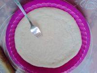 2、培根披萨,回温后的面团，擀薄，我这里做的是10寸的厚底披萨，如果不想做这么大，或者是做薄底的，可以把面团分成两份做两个8寸的。放入披萨盘，用叉子叉出小洞