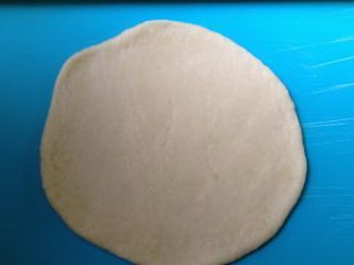 6、彩蔬培根牛肉粒披萨,取五分之一面团,揉搓后,擀成圆饼,厚薄随心意,擀的厚度要小于想要的成品厚度,因为熟制过程中会发大些