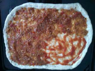 2、自制【香肠披萨】,准备好的披萨皮铺满披萨酱。